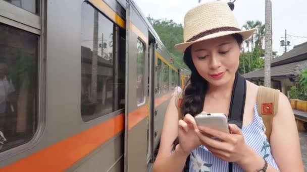 アジアの女性のテキスト メッセージ彼女の友人と彼女は台中に向かっていることを伝えます 彼女は古い鉄道鉄道鉄道の横に立っています — ストック動画