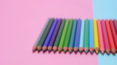 Çok renkli renkli kalemler düzgün bir şekilde masanın üzerine yerleştirilir. Bir punchy pastel arka plan üzerinde.