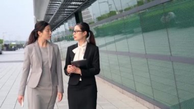Asyalı kadın iş Sekreter ve ofis binası dışında dijital tablet ile birlikte konuşurken yürüyüş Yöneticisi.