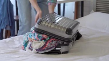 giysi ve aksesuarları valizin içine sıkma Asyalı kadın hızlı hareketi. Yakın çekim bir vuruşta.