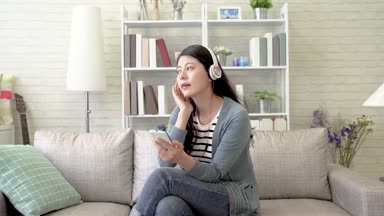 Asyalı kadın oturma odasında ve sallanan ve müzik hoş onu sırasında Pazar öğleden sonra şarkı zevk.