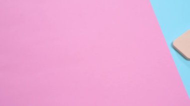 Bir dikdörtgen göz farı ve bir toz puf bir pembe ve mavi masanın üzerine koydu. Bir punchy pastel kavram.