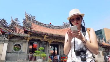 Asyalı Genç kız bir antik tapınak ve Longshan Tapınağı önünde onun telefonu sonraki hedef aramak için aramaya başladı.