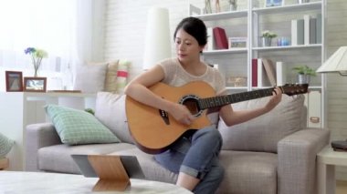 Asyalı kadın onun dijital tablet kullanma onun gitar tuning. Touchpad üzerinde videoları görerek oynamayı öğrenmek istedi.