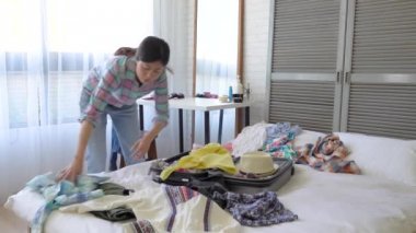 Asyalı tembel kadın sıkma ve bavul rahat onun takım elbise paketleme hızlı bir hareket.