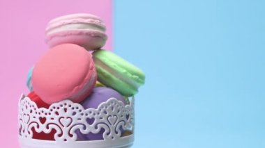 Plastik bir sürü sahte bir yığın halinde yığılmış macaroons ve bir punchy pastel arka plan üzerinde döndürün.