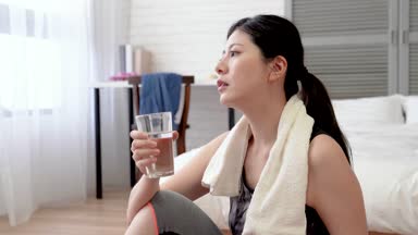 Terli bir kadın onu egzersiz ve oturup bir mola almak için yoga mat yapıyor bitirdi. O onun ter havlu mendil ve bir bardak su içtim.