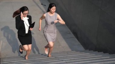 İki Asyalı güzel benzetmeler acele yürüyen merdivenlerde. bir telefon ve izlemek merdiven üzerinde çalışan diğer bir baksam konuşurken.