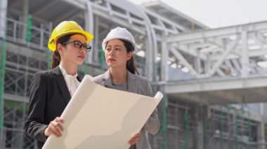 kadın iş mühendisleri inşaat yöneticileri açık havada site planları tartışma ile binasında.
