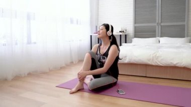 Asyalı kadın akıllı telefon ve kulaklık ile müzik. O şımartmak kendini müzik ve aynı zamanda görünümü windows dışında görmek.