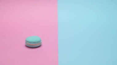 Macaron masaya yuvarlandı ve maviyi durdu. Punchy pastel arka plan üzerinde.