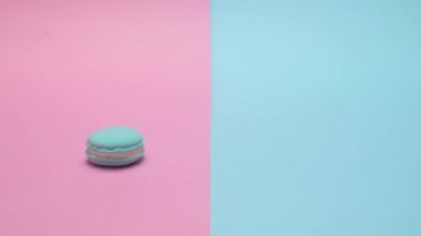 Macaron masaya yuvarlandı ve maviyi durdu. Punchy pastel arka plan üzerinde.