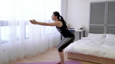 Asyalı kadın çömelme aşağı ve denge zaman bir süre için devam edin..