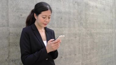 Akıllı telefon konuşmayı duvara yaslanmış güzel iş kadını.