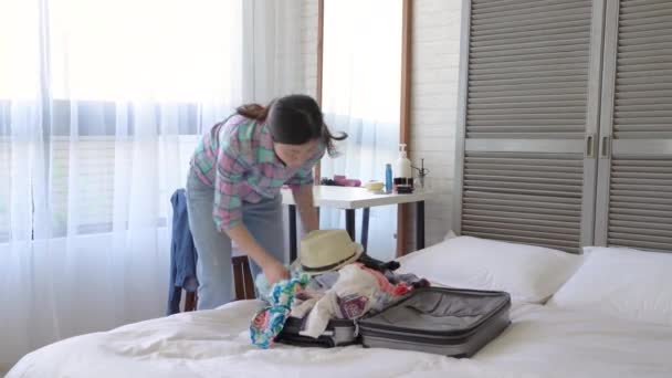 アジアの怠惰な女の子が彼女のスーツケースとまま寝室を梱包のプロセス — ストック動画