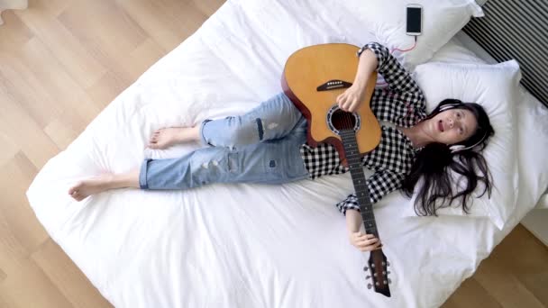 Wanita Asia Berbaring Tempat Tidur Memakai Headphone Dan Mendengarkan Lagu — Stok Video