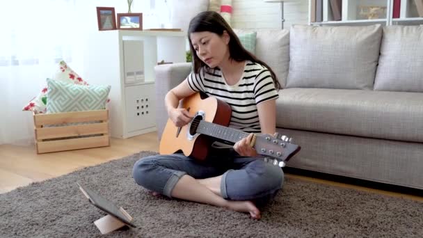 Asian Woman Follows Online Video Learn How Play Wooden Guitar — Stock Video