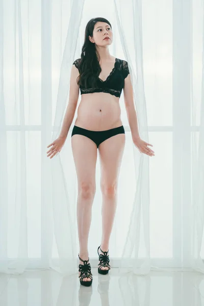 Mulher grávida sexy em saltos altos entre cortina — Fotografia de Stock