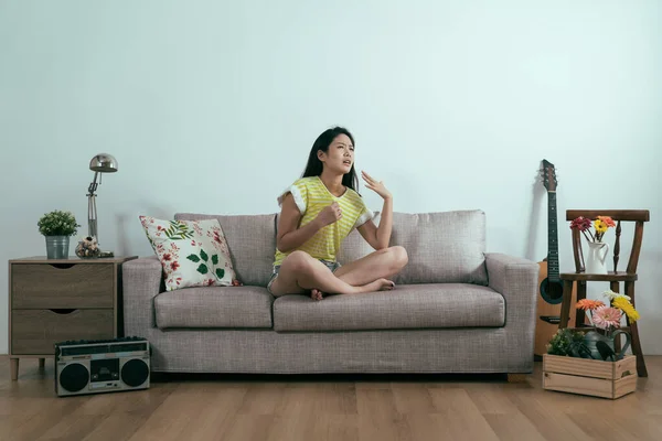 Жінка в літньому одязі сидить на комфортному дивані — стокове фото