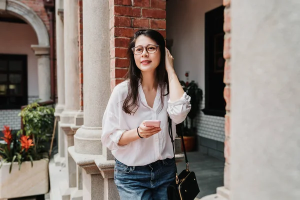 Girl leans brick pillar with smart phone in hands — Stock Photo, Image