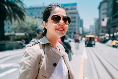 Kadın arkada teleferikle yolda duruyor..