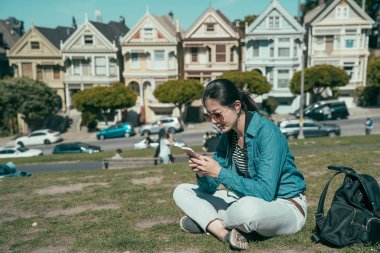 Gezgin çimlerde rahatlar ve cep telefonuyla mesajlaşır..
