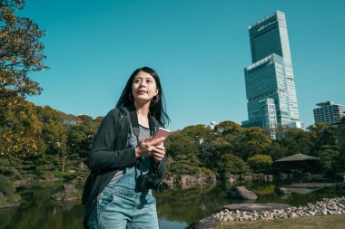 Kız gezgin cep telefonuyla gün ışığının tadını çıkarıyor.