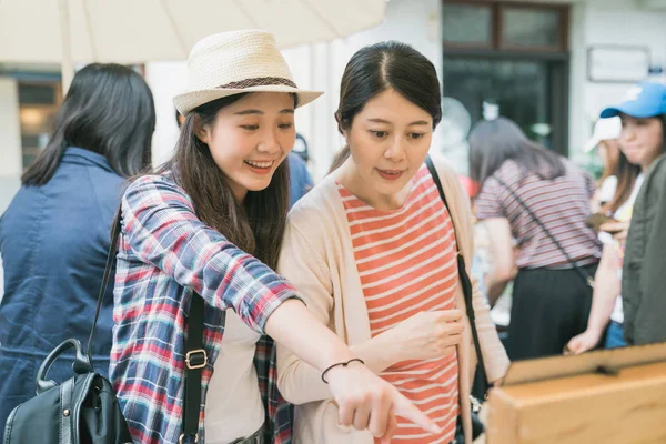 Surprised girl showing friend product on vendor — Stock Photo, Image