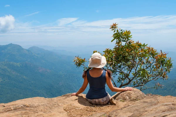 Happy woman enjoying nature on top of mountain cliff