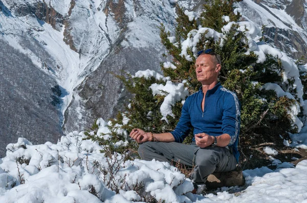 Meditating man in snowy Himalayan mountains