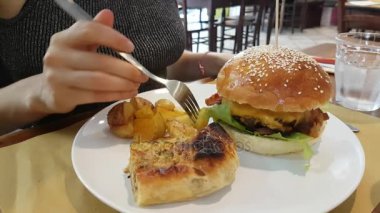 Genç kadın patates ve Hamburger restoranda yemek