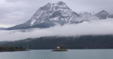 Serre-Poncon Gölü 'nün üzerindeki Bulutların Üzerindeki Zaman Çizelgesi Saint-Michel Şapeli ve kışın Karla kaplı Grand Morgon Tepesi. Hautes-Alpes, Fransız Alpleri, Fransa, Avrupa - DCi 4K Kararı