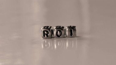 Roi - return on investment - word from metal blocks - concept sepia tone photo on shine background clipart