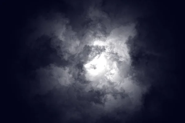 Moonlight through clouds in stormy sky - background with hurrigane swarms - night sky during the onset of a hurricane