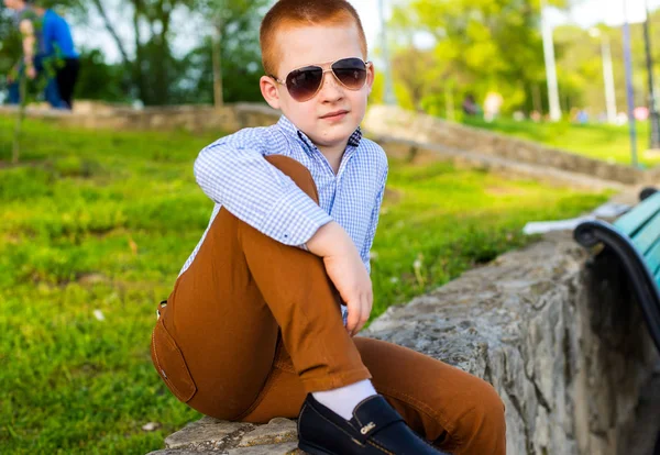 Stylish baby boy with ginger hair in trendy sunglasses