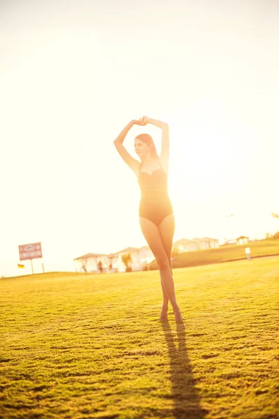 Feliz hermosa mujer en bikini en la hierba verde en la puesta del sol . — Foto de Stock