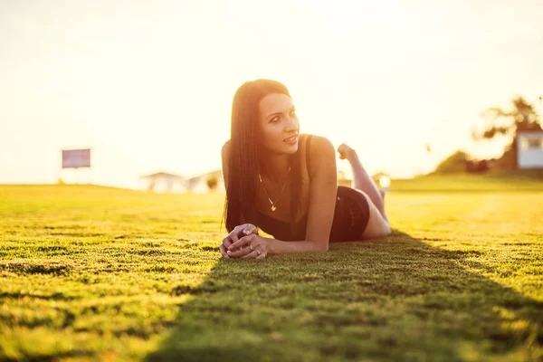 Mulher bonita feliz em biquíni na grama verde no pôr do sol . — Fotografia de Stock