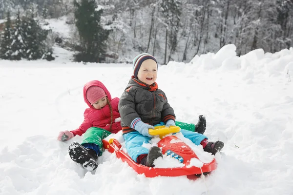 Hermano y hermana en trineo en un paisaje nevado de invierno — Foto de Stock