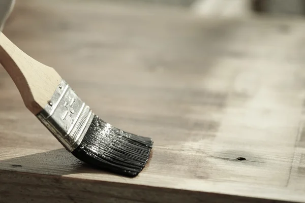Paintbrush sliding over wooden surface, protecting wood — Stock Photo, Image