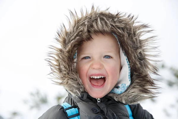 Блакитноокий маленький хлопчик в зимовому пейзажі, посміхаючись — стокове фото
