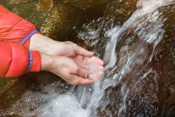 Thirsty hiker drinking water from a crystal clear spring — Stock Photo, Image