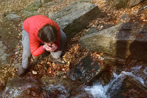 Caminhante sedento bebendo água de uma fonte cristalina — Fotografia de Stock