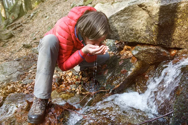 Senderista sediento bebiendo agua de un manantial cristalino — Foto de Stock