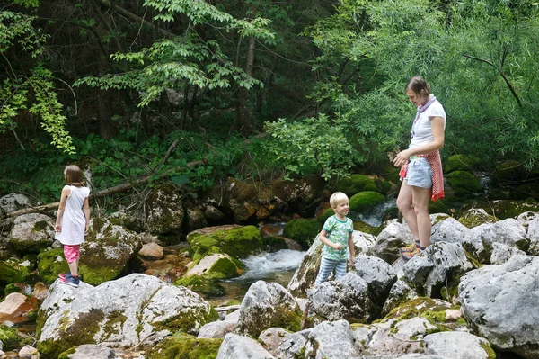 Mother with children having fun, playing by a mountain creek in summer. — Stock Photo, Image