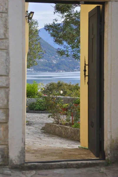 Deniz ve dağ arka planda bir bahçe için davetkar açık kapı.