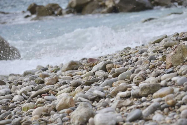 Arka planda deniz dalgası ve sıçrama ile Çakıl plaj