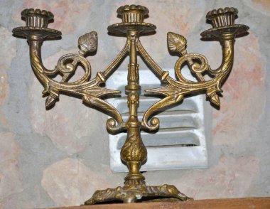 Arka planda taş duvar olan mumsuz eski bir şamdan.