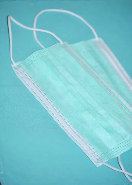 Mavi tekstil arka planında iki cerrahi maske