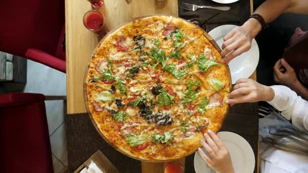 Hände nehmen Pizzastücke vom Teller auf den Tisch. — Stockvideo