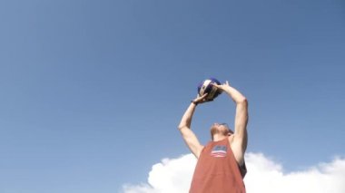 Mavi gökyüzü altında volley ball oyunu oynayan adam.